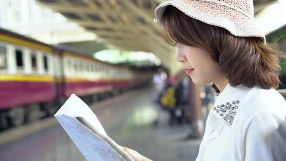Happy young female direction and looking on location map at train station before travel.