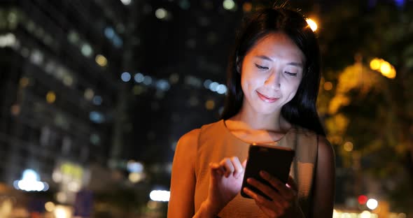 Woman use of smart phone in city at night 