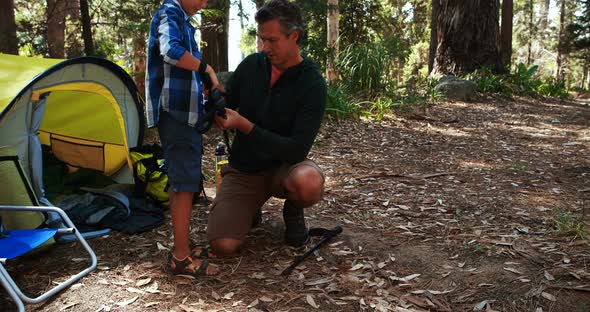 Father teaching son to use trekking pole outside tent