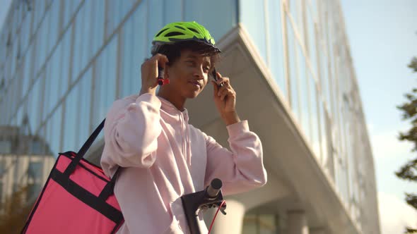 African Delivery Man Putting on Helmet Riding Electric Kick Scooter Carrying Thermal Box