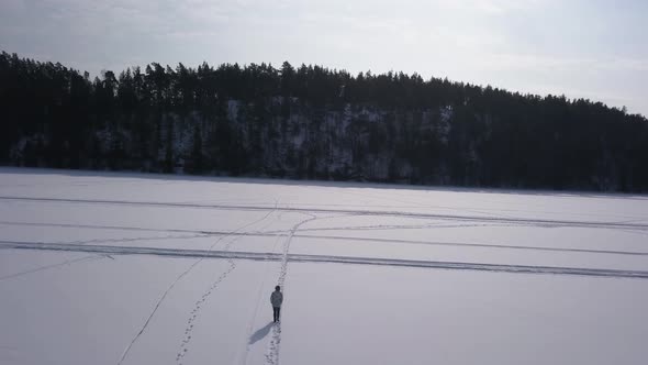 Young blonde female going for walk on desolate frozen lake to clear her mind from everyday living.