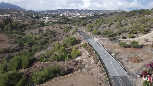 Flight over the road in the mountains. Rural landscapes. Summer afternoon. Clouds. Cyprus