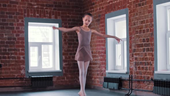 A Little Ballerina Girl Performing Basic Dancing in the Studio and Stands in the Position Looking in