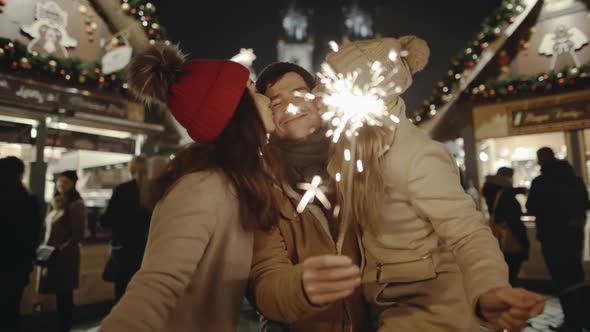 Smiling Pretty Women and Handsome Man Kissing and Dancing with Bright Sparklers in the Centre of