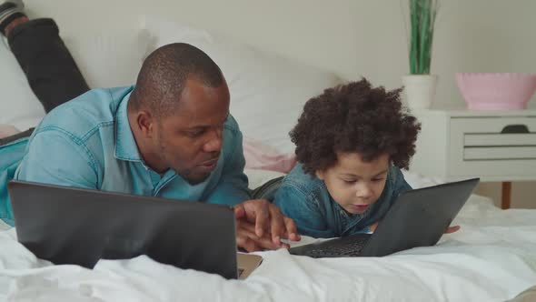 Caring Black Dad Teaching Son Using Laptop at Home