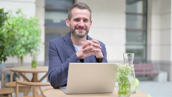 Man Smiling at Camera While Using Laptop Outdoor