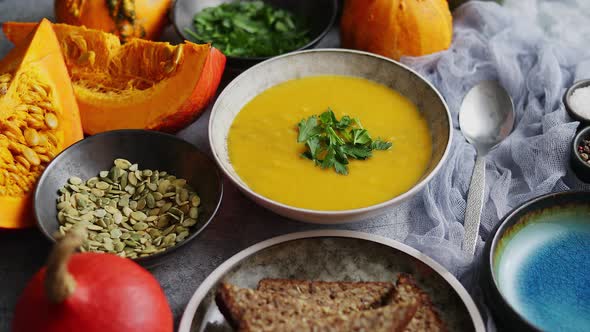 Pumpkin Soup Decorated with Parsley for Thanksgiving, Halloween. Placed on Grey Stone Background