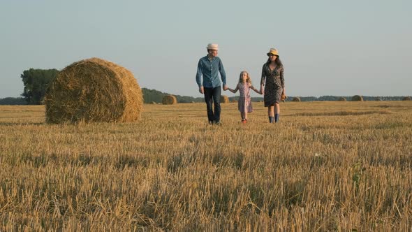 Family of Three Walking in a Harvested Field