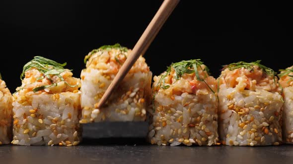 Take One Sushi Roll From Black Slate Board Using Chopsticks