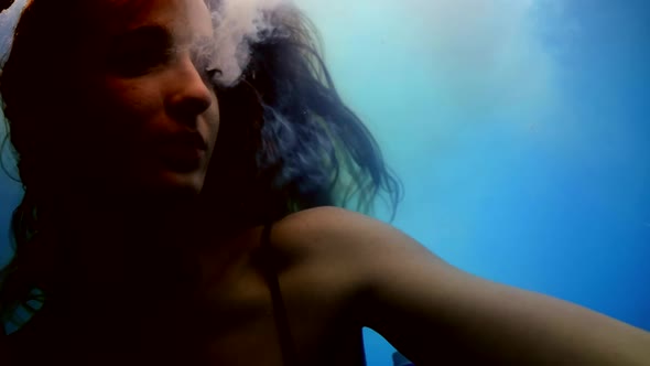 Woman is Exhaling Smoke and Floating in Water of Large Aquarium Underwater Slow Motion Shot