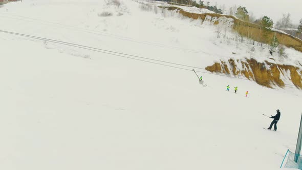 Skier on Skies Rises on Snowy Hill By T-bar Lift Aerial View