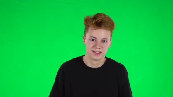 Portrait of Ginger Teenager Boy with a Tattoo Is Having Fun on a Green Screen
