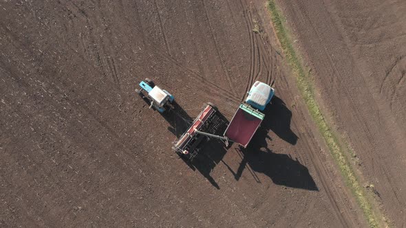 Aerial View of Tractor with Mounted Seeder Performing Direct Seeding of Crops on Plowed Agricultural