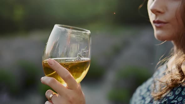 A Woman is Holding a Glass of Red Wine at Sunset