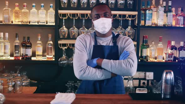 African Waiter in a Face Mask is Smiling Behind the Bar