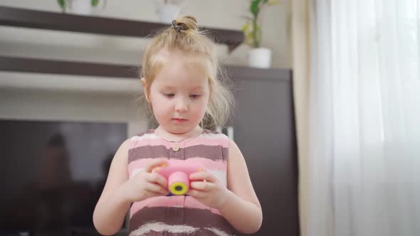 a Funny Little Girl Takes a Photo on a Little Pink Toy Camera