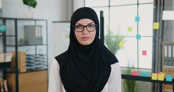Arabic Businesswoman in Hijab Looking Into Camera on the Background of Modern Office room