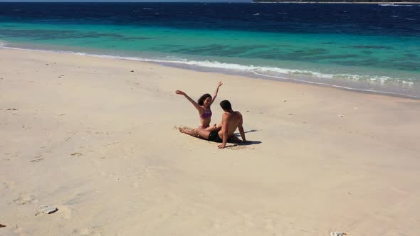 Two people happy together on luxury coast beach vacation by blue ocean with bright sandy background 