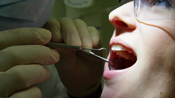 Dentist examining a female patient with tools