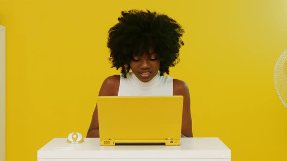 Happy AfroAmerican Woman Uses Yellow Laptop