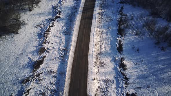 Aerial View of an Asphalt Road Surrounded By Snow in the Countryside