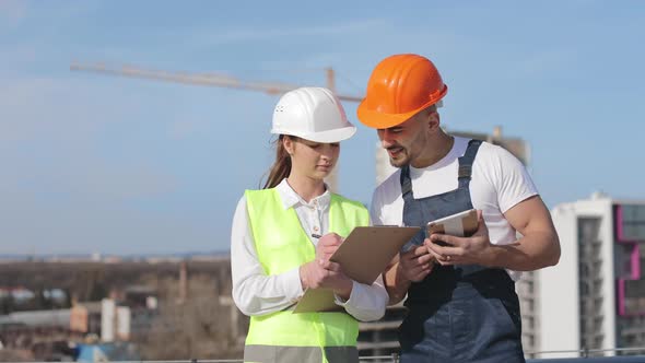 Two Young Engineers are Discussing Working Documents