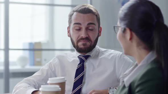 Coworkers Drinking Coffee and Chatting at Workplace