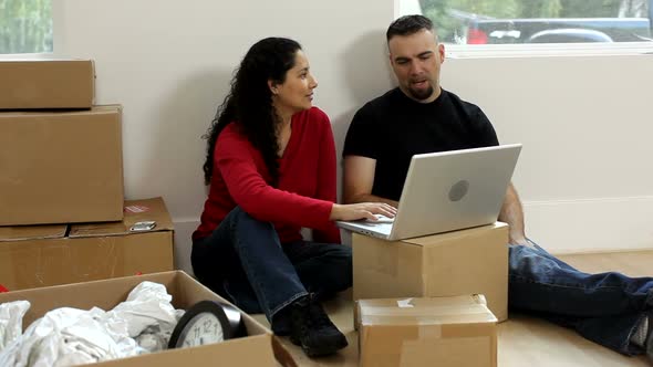 Couple with unpacked boxes looking at laptop