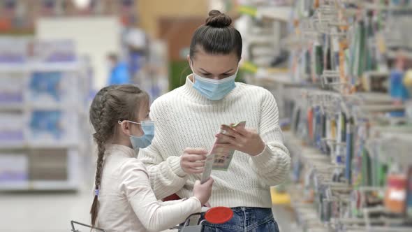 Mother and Child Wearing Protective Masks Choose Stationery at the Supermarket