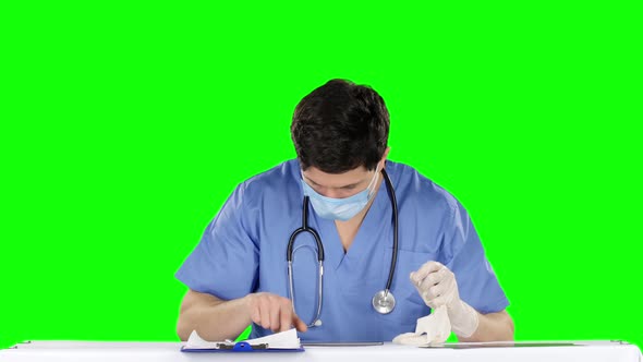 Doctor Removes Medical Gloves and Using Laptop. Green Screen