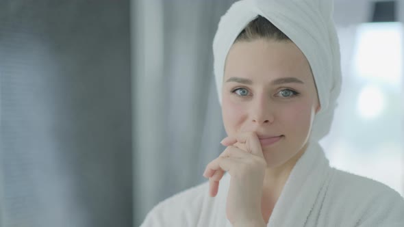 Close up portrait of young brunette woman looking in the mirror after shower at home