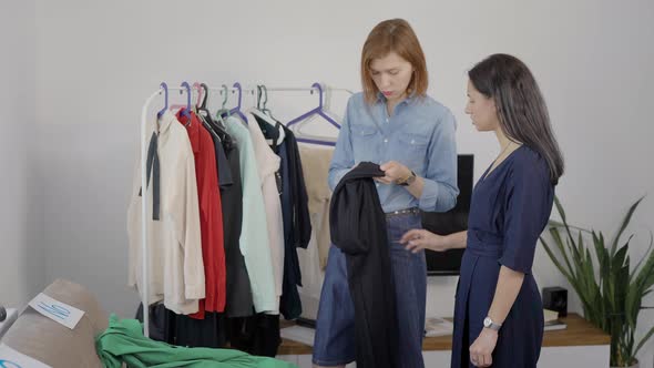 Two Beautiful Young Women Are Engaged in the Analysis of the Wardrobe. Girlfriends Choose Outfits