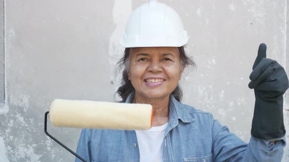 Portrait of a happy senior female Asian worker or painting roller.