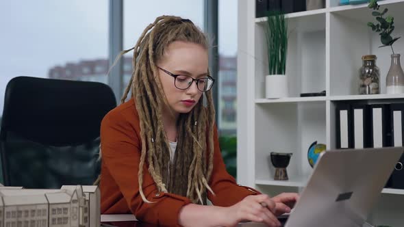 Female Engineer-Designer with Dreadlocks Working on Laptop in Modern Design Studio Agency