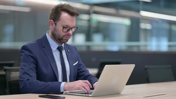 Middle Aged Businessman with Laptop Saying No By Finger Sign