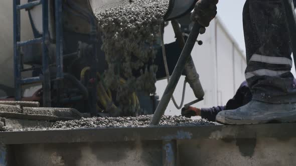 Workers pouring concrete into large steel molds on a construction site
