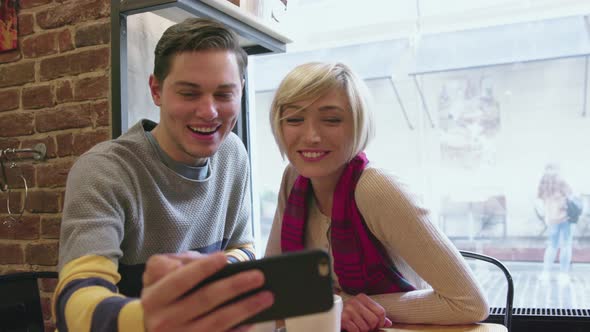 Video call. Happy couple in cafe using phone for video chat