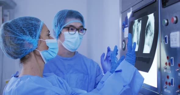 Diverse male and female surgeons wearing surgical caps and face masks discussing x ray