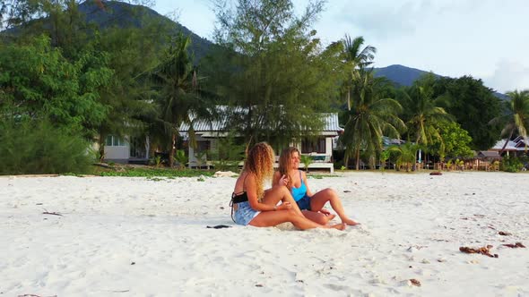 Tourists tanning on tranquil coastline beach lifestyle by blue green sea and white sand background o