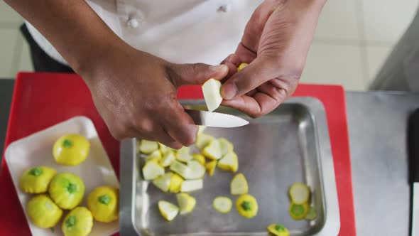 Midsection of mixed race male chef cutting vegetable in restaurant kitchen