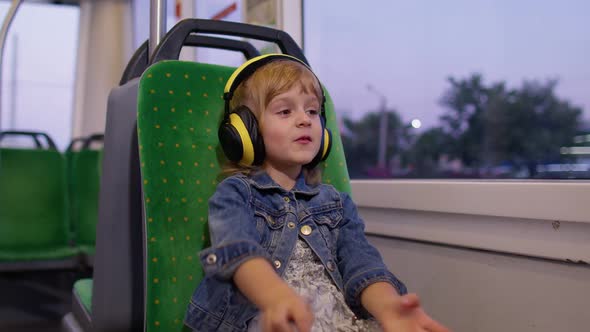 Lovely Child Girl Wearing Headphones Listening Music Relax Dancing While Traveling By Bus in City