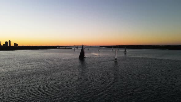 Colourful afternoon sunset sailing boat race along the calm waters of a city harbor. Moving high dro