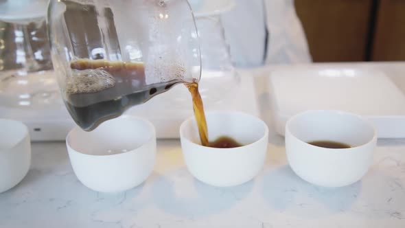 The Barista Arranges and Pours the Finished Coffee From the Filter Into White Cups