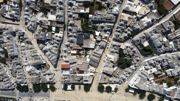 Aerial drone top wide shot of small walking streets around Alberobello, Italy. whitewashed stone hut