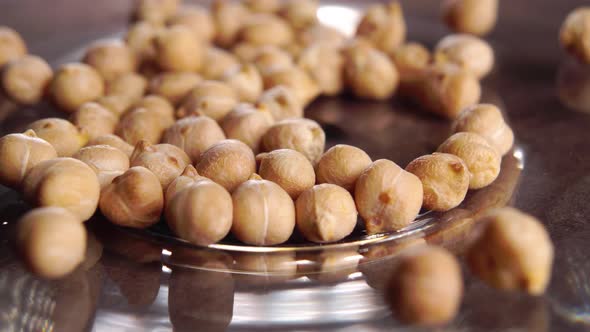 Dry chickpea beans in a shiny plate. Macro. Rotation