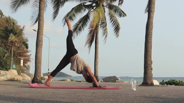Sporty Woman Doing Workout On Yoga Mat By The Ocean Coast. Healthy Lifestyle. wide shot
