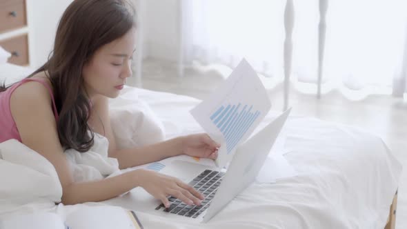 Beautiful freelance asian woman working and typing with laptop computer.