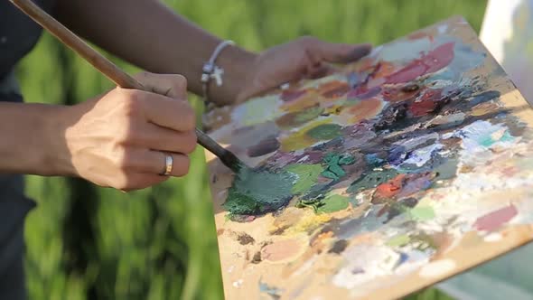 A professional artist paints a picture with oil paints.