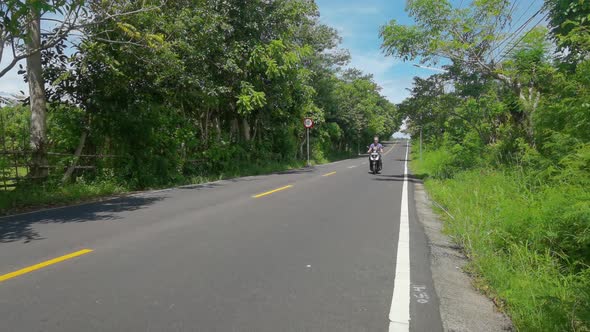 Young Man Ride on Scooter Through Green Alley