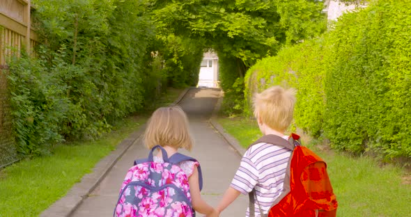 Adorable brother and sister holding hands as they walk to school together